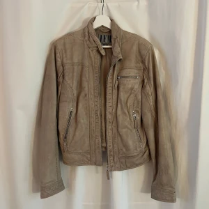 Beige läderjacka från Jofama - Säljer en snygg beige skinnjacka från Jofama i mycket bra skick. Perfekt för höst och vår, och ger en stilren look. Passar till både vardag och fest! Knappt använd, men köpt second hand via Sellpy.