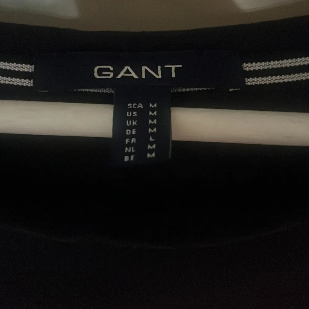 Säljer en snygg svart t-shirt från GANT med vit text 'GANT Est. 1949' på bröstet. Perfekt för en casual look! T-shirten är i mycket bra skick och passar till både jeans och kjol. Skön och stilren design som funkar året runt. . T-shirts.