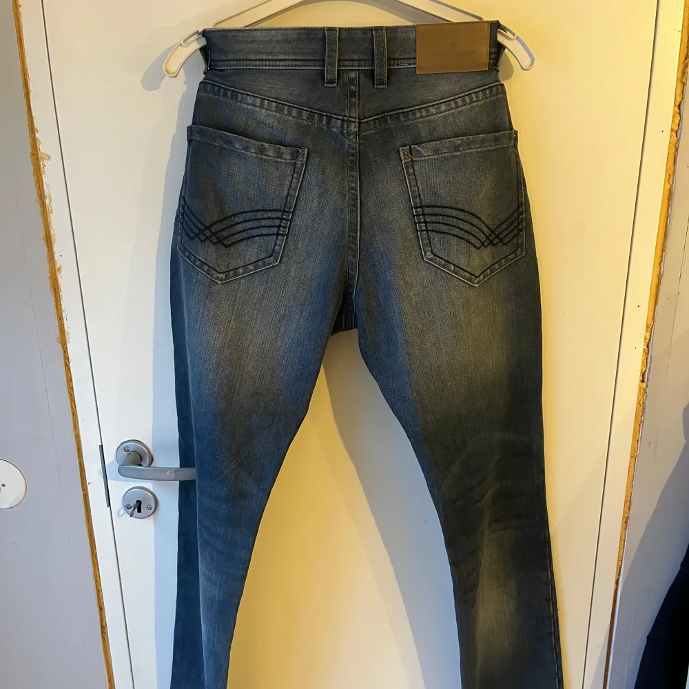 Säljer ett par snygga blå jeans från Tom Tailor, modell Josh. De har en regular slim passform och är i bra skick. Perfekta för både vardag och fest! De är tillverkade i slitstarkt denim och har en snygg tvättad look. Storlek 30/34. Jeans & Byxor.