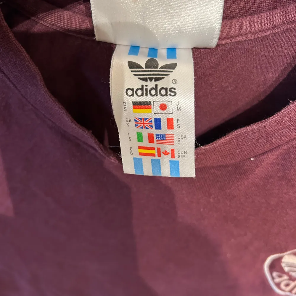 Säljer en snygg vinröd stora t-shirt från Adidas i mycket bra skick. Den har korta ärmar och klassiska Adidas-ränder på axlarna. Perfekt för både vardag och träning. Märket syns på bröstet och materialet är mjukt och bekvämt.. T-paidat.