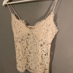 Beige/ljusrosa spetslinne - Säljer ett superfint beige blommigt spetslinne med tunna axelband och dragkedja på sidan. Perfekt för sommardagar eller festliga tillfällen. Det har en vacker blommig spetsdesign som ger en romantisk känsla. Linnet är i mycket bra skick och passar perfekt till både jeans och kjol. (PM OM DU VILL HA FLER BILDER)