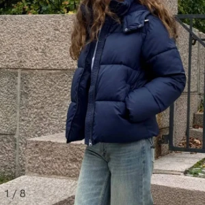 Mörkblå pufferjacka - Intressekoll på min mörkblå pufferjacka från Nelly i nytt skick endast använd några få tals gånger. Den är perfekt för kalla dagar med sin tjocka vaddering och har en praktisk huva. Jackan har en dragkedja framtill och långa ärmar. Supermysig och varm för vintern! 🖤