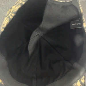 Ferragamo keps - Snygg keps med ett unikt mönster i beige och svart. Perfekt för att ge din outfit en cool touch. Kepsen har en klassisk passform och är tillverkad i ett slitstarkt material. Passar både till vardags och för speciella tillfällen. Kan ej garantera att den är äkta