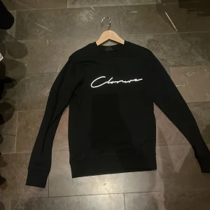 Svart sweatshirt från Closure London - Säljer en stilren svart sweatshirt från Closure London i storlek XS men sitter som S. Tröjan har en vit text på bröstet och är perfekt för en casual look. Den är i mycket bra skick och passar både till vardags och chilliga kvällar. Skön och enkel att matcha med det mesta!