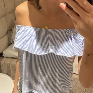 Randig offshoulder volang topp - Säljer en superfin blå- och vitrandig offshoulder topp med volangdetalj. Supersomrig tröja verkligen. Toppen är i ett lätt och bekvämt material, perfekt att matcha med shorts, kjol eller jeans! Använd några somrar men inte ofta, inga märken eller defekter! I storlek 146/152 men jag brukar ha xs/ på toppar och den passar perfekt!