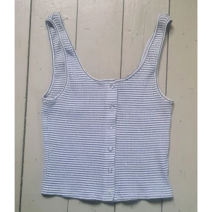 Croppat linne med knäppning, ribbad randig svart/vit S - Bra skick utöver några vita färgstänk. 95% bomull, 5% elastan. Vidd: 31, längd: 39.