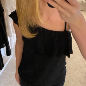 Svart oneshoulder topp från KappAhl - Snygg svart oneshoulder topp från KappAhl i storlek 36. Toppen har en elegant volangdetalj och är tillverkad i ett mjukt material som ger en bekväm passform. Ett måste i garderoben för alla som älskar stilrena plagg!