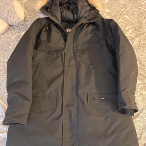 Canada Goose - Säljer en svart parkajacka ifrån Canada Goose som är köpt på johnells för 2 år sedan, men som fortfarande är i mycket bra skick. Jackan är perfekt för vintern med sin varma dunfyllning och har en snygg pälsdetalj på huvan. Den har långa ärmar och praktiska fickor framtill. Perfekt för kalla dagar. Priset kan diskuteras vid snabb affär.    Har du fler frågor hör gärna av dig! 