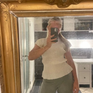 Figursydd topp - En figursydd vit topp i lite ”räfflat” material. Väldigt fin och lätt att klä upp och ned. Storlek S.