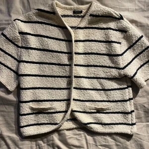 Randig jacka från Massimo Dutti - Säljer en snygg randig kofta från Massimo Dutti i beige och svart storlek M. Den har korta ärmar och knappar framtill. Perfekt för vår och sommar med sitt stilrena mönster och bekväma passform💕