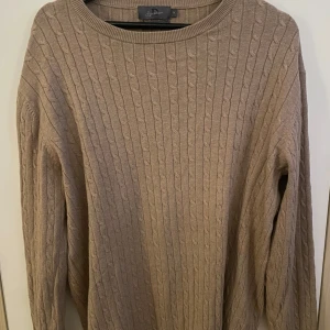 Beige kashmirblandad tröja från Signature - Säljer en supermjuk och stilren beige tröja från Signature i kashmirblandning. Den har ett klassiskt kabelstickat mönster och långa ärmar, perfekt för kyliga dagar. Passar både till vardags och lite finare tillfällen. Ett måste i garderoben för höst och vinter! 🍂