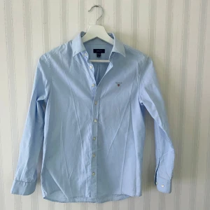 Ljusblå skjorta från GANT - Säljer en stilren ljusblå skjorta från GANT i storlek 146/152. Perfekt för både vardag och finare tillfällen