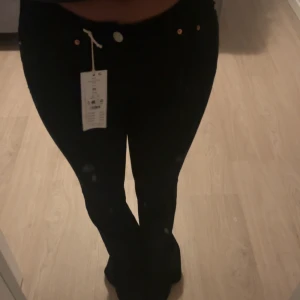 Svarta bootcut jeans - Säljer ett par svarta bootcut jeans i nytt skick. De är högmidjade och har en klassisk femficksdesign med knappar, den är helt ny och oanvänd, prislapp sitter kvar