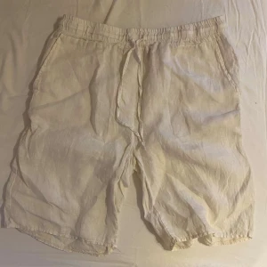 Vita linne shorts - Säljer ett par vita linne shorts i loose fit. Perfekta för sommaren med elastisk midja och snörning för extra komfort. De har två sidofickor och en bakficka. Superlätta och luftiga, idealiska för varma dagar! Dom är i storlek 164 men passar 170 skulle jag säga. Dom är köpta från kidsbrandatore för 350kr använda 4 gånger
