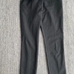Nya grå kostymbyxor i strl 40 från Morris, modell Morgan Trousers - Nya grå kostymbyxor i strl 40 från Morris, modell Morgan Trousers.  Nya, aldrig använda.  Mått Midjan: ca 42 cm Längd från grenen och ner: ca 75 cm  54% polyester, 44% ull och 2% elastan  Kommer från ett djur och rökfritt hem.