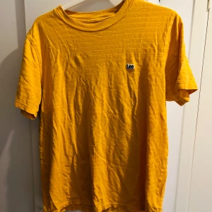 Gul t-shirt från Lee - Säljer en snygg gul t-shirt från Lee i storlek M. Den är i bra skick och perfekt för sommardagar. T-shirten har en normal passform och är gjord av mjukt bomullsmaterial. Den har korta ärmar och en liten Lee-logga på bröstet. Perfekt för en avslappnad stil! 🌞