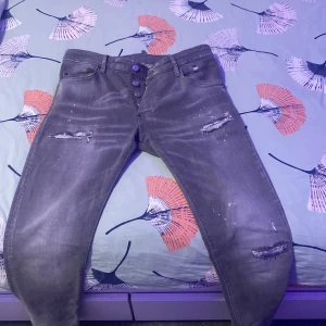 Grå jeans från Dsquared2 - Säljer ett par grå jeans från Dsquared2 i bra skick. De har en cool slitningseffekt och knappar framtill. Perfekta för en avslappnad stil med en edgy touch. Passar bra till både vardag och fest!