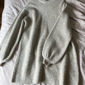 Stickad klänning  - En ljusljus beige stickad klänning med långa ärmar och rund halsringning. Klänningen har en rak passform och är tillverkad i ett mjukt och bekvämt material. Använd 2 gånger! 