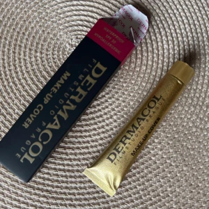 Dermacol Make-Up Cover - Säljer en Dermacol Make-Up Cover i en snygg guld tub. Denna foundation är känd för sin höga täckning och hållbarhet. Perfekt för att dölja ojämnheter och ge en jämn hudton. Kommer i originalförpackning med svart och rosa detaljer. Perfekt för både vardag och fest!