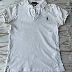 Säljer en klassisk vit pikétröja från Polo Ralph Lauren. Den har korta ärmar och en broderad logga på bröstet. Perfekt för en stilren och avslappnad look. Passar både till vardags och lite finare tillfällen. 🕶️