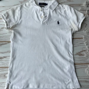 Vit pikétröja från Polo Ralph Lauren - Säljer en klassisk vit pikétröja från Polo Ralph Lauren. Den har korta ärmar och en broderad logga på bröstet. Perfekt för en stilren och avslappnad look. Passar både till vardags och lite finare tillfällen. 🕶️