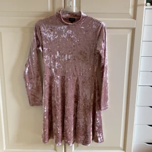 Rosa sammet klänning från Bubbleroom - Säljer en superfin rosa sammet klänning från Bubbleroom. Den har en glittrig yta och är långärmad med en normal passform. Perfekt för festliga tillfällen! Klänningen är i storlek M och har en mjuk och bekväm känsla.