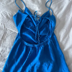 Blå klänning med volangdetaljer - Säljer en superfin blå klänning med smala axelband och volangdetaljer. Perfekt för sommardagar eller en festlig kväll. Klänningen är gjord i ett lätt och bekvämt material.