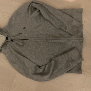 Grå hoodie från Ralph Lauren - Säljer en snygg grå hoodie från Ralph Lauren i storlek S. Den har en dragkedja framtill och är tillverkad i mjukt material för extra komfort. Perfekt för både höst och vår. Den har långa ärmar och en klassisk design med en liten logga på bröstet. Nästan aldrig använd!