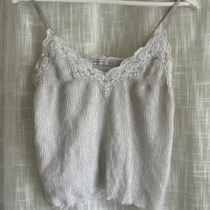 Vit linne från Stradivarius - Säljer ett superfint vitt linne från Stradivarius i storlek S. Det har tunna axelband och vacker spetsdetalj vid halsringningen. Tecken på användning men ändå fin!