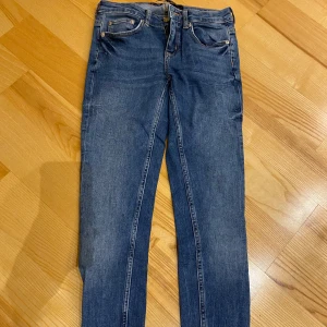 Blå skinny jeans från Denim Rebel - Säljer ett par snygga blå stretchiga jeans från Denim Rebel. De har en tight passform och är perfekta för både vardag och fest. Jeansen har coola dragkedjor vid anklarna som ger en extra edge. De är i bra skick och redo för en ny ägare! Strl 34, eller XS