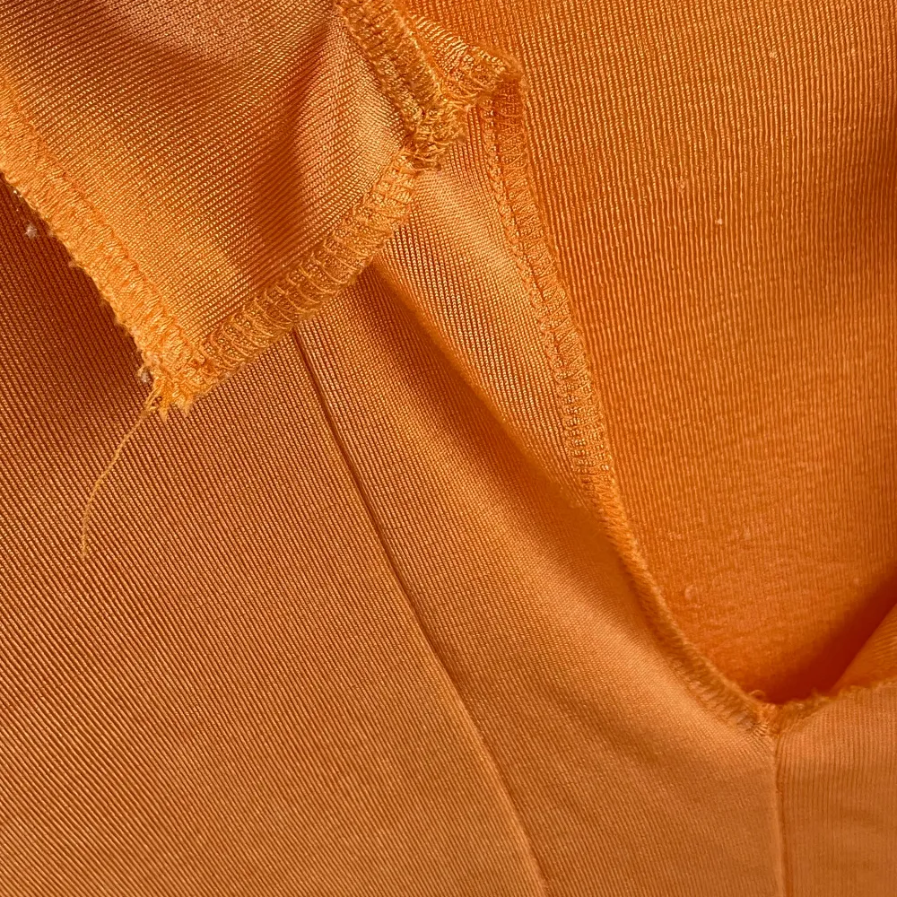 Säljer en snygg orange långärmad topp i ett mjukt och stretchigt material. Toppen har en v-ringad design och en stilren look som passar perfekt till både vardag och fest. Den är i bra skick och redo för en ny ägare!. Yläosat.