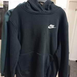 Säljer en klassisk svart hoodie från Nike i storlek M (137-147). Den är superbekväm och perfekt för både vardag och träning. Hoodien har en känguruficka och det ikoniska Nike-loggan på bröstet. Perfekt för höst och vinter!