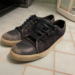 Svarta sneakers från Lanvin - Snygga svarta sneakers från Lanvin med snörning och en robust sula. Skorna har en stilren design med en ovandel i mocka och detaljer i skinn. Perfekta för en avslappnad men stilfull look.