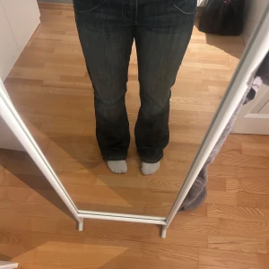 Blå bootcut jeans - Snygga vintage blå bootcut jeans med klassisk femficksdesign. De har en lätt slitning vid fållen som ger en cool, avslappnad look. Perfekta för en casual stil.
