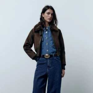 Brun mockajacka med pälsdetaljer från Zara strl XL - nyskick! - Snygg brun mockajacka från Zara med mjuk pälsdetalj på kragen. Jackan har dragkedja framtill och ribbade muddar vid ärmslut och nederkant. Perfekt för kyliga dagar!