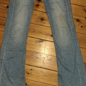 Blå bootcut jeans från Kappahl - Snygga blå bootcut jeans från Kappahl i storlek 158. De har en klassisk femficksdesign och knappar i midjan. Perfekta för en avslappnad stil med en touch av retro. Men har en liten grässfläck på ett av knänen.