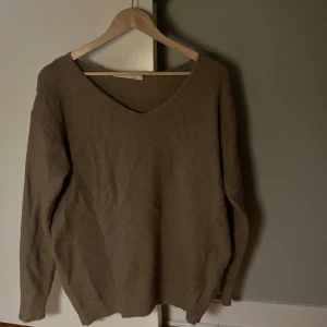 Brun v-ringad tröja - Säljer en brun v-ringad tröja med långa ärmar. Perfekt för kyligare dagar och enkel att matcha med olika outfits. Tröjan har en avslappnad passform och är gjord i ett mjukt material.