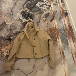 Beige croppad jacka - Säljer en beige croppad jacka med knappar framtill. Jackan har långa ärmar och är storlek XS från hm. pris kan diskuteras 