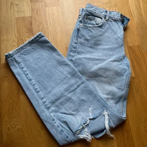 Blå jeans med slitningar Gina Tricot - Petite  - Petite längd. Enda defekten är att slitningarna dragit mot sidorna efter tvätt men annars inga defekter, knappar istället för gylf (se bild) finns även bild på midje och innermått! skriv i chatten ifall du vill se baksidan (nått maxantal på bilder) 