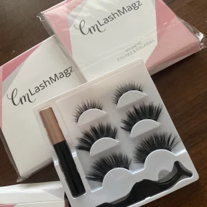 Magnetiska lösögonfransar med eyeliner från CmLashMagz - 100 kr st. Set med magnetiska lösögonfransar och en svart magnetisk eyeliner. Innehåller flera par fransar i olika stilar för varierande look. Perfekt för att enkelt få fylliga och dramatiska fransar utan lim. Inkluderar även en applikator för enkel applicering.