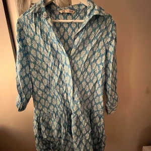 Blå blommig klänning från Zara - Säljer en söt blå klänning från Zara med vitt blommönster. Klänningen har trekvartsärmar och en avslappnad passform. Perfekt för en somrig look! 🌸