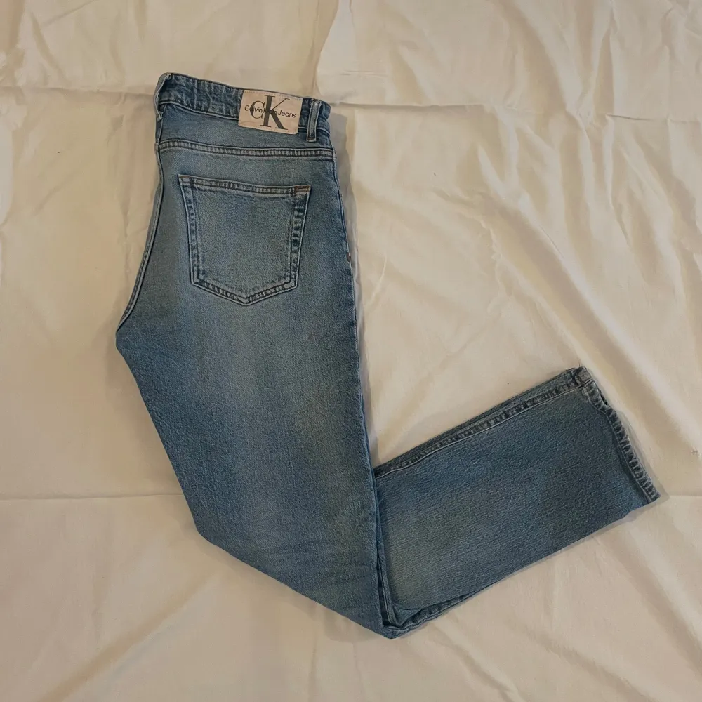 Snygga blå jeans från Calvin Klein med en klassisk femficksdesign. De har en normal passform och är perfekta för en avslappnad stil. Jeansen har en knappgylf och är tillverkade i ett slitstarkt denimtyg. Jeansen är i storlek 16years och har en defekt på knät därav billigt pris. Om du har någon fundering är det bara att höra av sig. Mvh Levi!. Farkut & Housut.