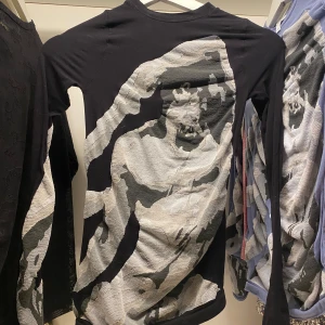 Svart långärmad tröja från Eytys - Säljer en svart långärmad tröja från Eytys med ett unikt mönster i grått och vitt på framsidan. Tröjan har en rund hals och är tillverkad i ett mjukt material. Använd endast en gång. Original pris 2000-2800