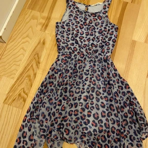 Leopardmönstrad klänning från H&M - Säljer en cool leopardmönstrad klänning från H&M. Klänningen är ärmlös och har en luftig passform med ett snyggt fall. Perfekt för att sticka ut med sitt djärva mönster. Den har en knappdetalj i nacken och är gjord i ett lätt och bekvämt material.