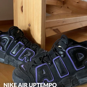 Nike Air Uptempo i svart och lila - Säljer ett par Nike Air Uptempo sneakers i svart med lila detaljer. Skorna har den ikoniska 'AIR' texten på sidorna och en synlig Nike-logga på hälen. Perfekta för dig som vill ha en sportig och trendig look. Skorna är i väldigt bra skick!