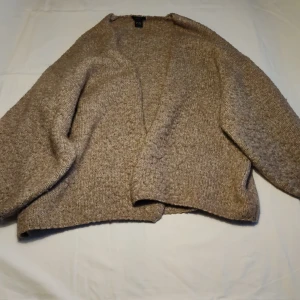 Beige stickad kofta från Lindex - Mysig beige stickad kofta från Lindex i storlek XL/XXL. Perfekt för kyliga dagar med sin mjuka och bekväma passform. Koftan har en öppen design utan knappar och långa ärmar.
