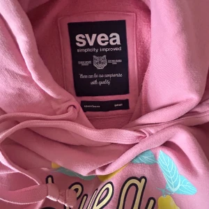 Rosa hoodie från Svea - Säljer en rosa hoodie från Svea med tryck av gula citroner och Svea-logga på framsidan🩷🍋Köptes i storlek S men passar även M!!             Perfekt nu till våren🤝🏼