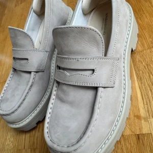 Beige loafers Vagabond cosmo 2.0 - Snygga beige loafers från Vagabond i skinn med robust sula. Perfekta för en stilren look. Skorna har en klassisk design med dekorativ rem över foten. Använda en gång ute. Namn: cosmo 2.0