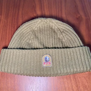 Olivgrön ribbad mössa från Parajumpers - Olivgrön mössa från Parajumpers. Fint skick! Storlek L-XL. Väldigt sparsamt använd. Leverans med PostNord eller Instabox, köparen står för frakten📦