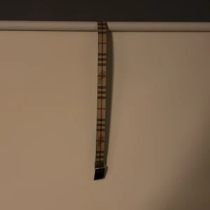 Rutig bälte från Burberry - Snyggt bälte från Burberry med klassiskt rutigt mönster i beige, svart och rött. Som är gjort i Italien ( se bild 4 ) bältet är 105 mc långt.